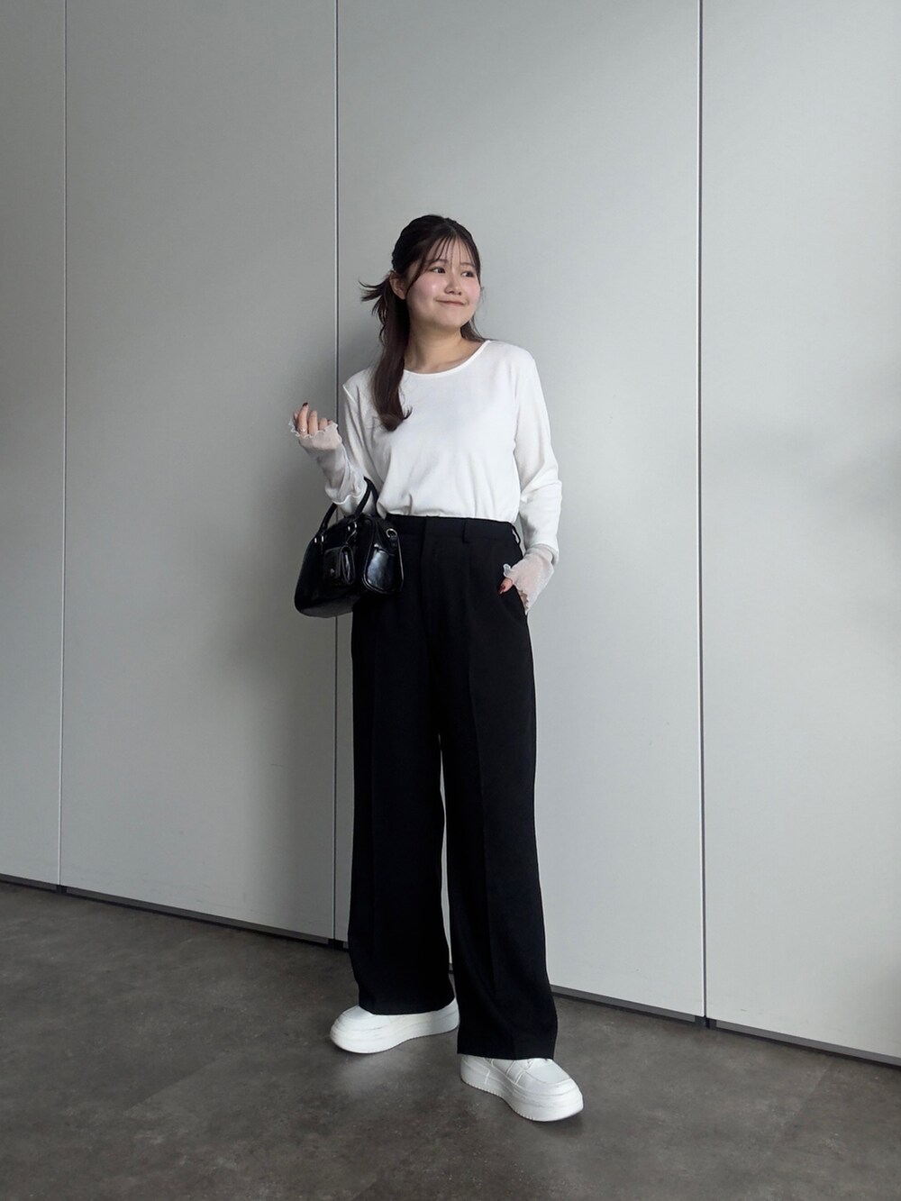 ホワイト系のTシャツ/カットソー、ブラック系のスラックス、ブラック系のボストンバッグを着用したレディースの春コーディネートの2枚目の写真