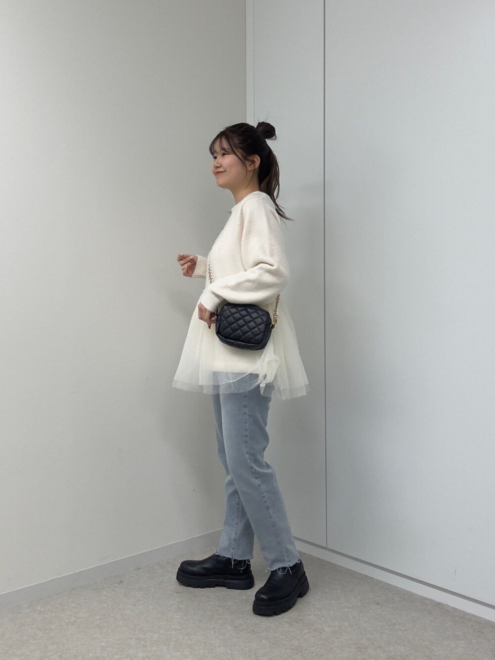 ホワイト系のニット/セーター、ブラック系のショルダーバッグ、ブルー系のデニムパンツを着用したレディースの冬コーディネートの2枚目の写真