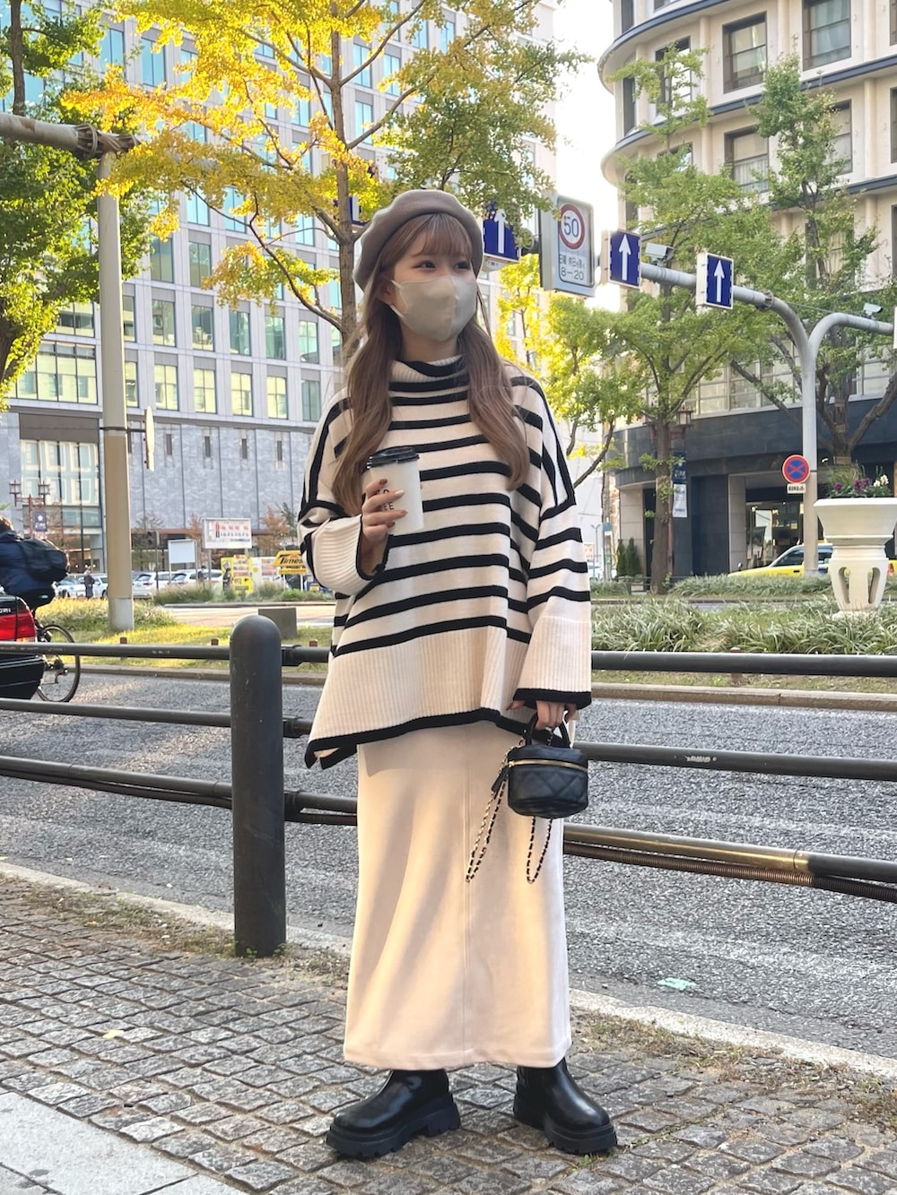 ホワイト系のスカート、ブラック系のブーツ、ブラック系のショルダーバッグを着用したレディースの秋コーディネートの3枚目の写真