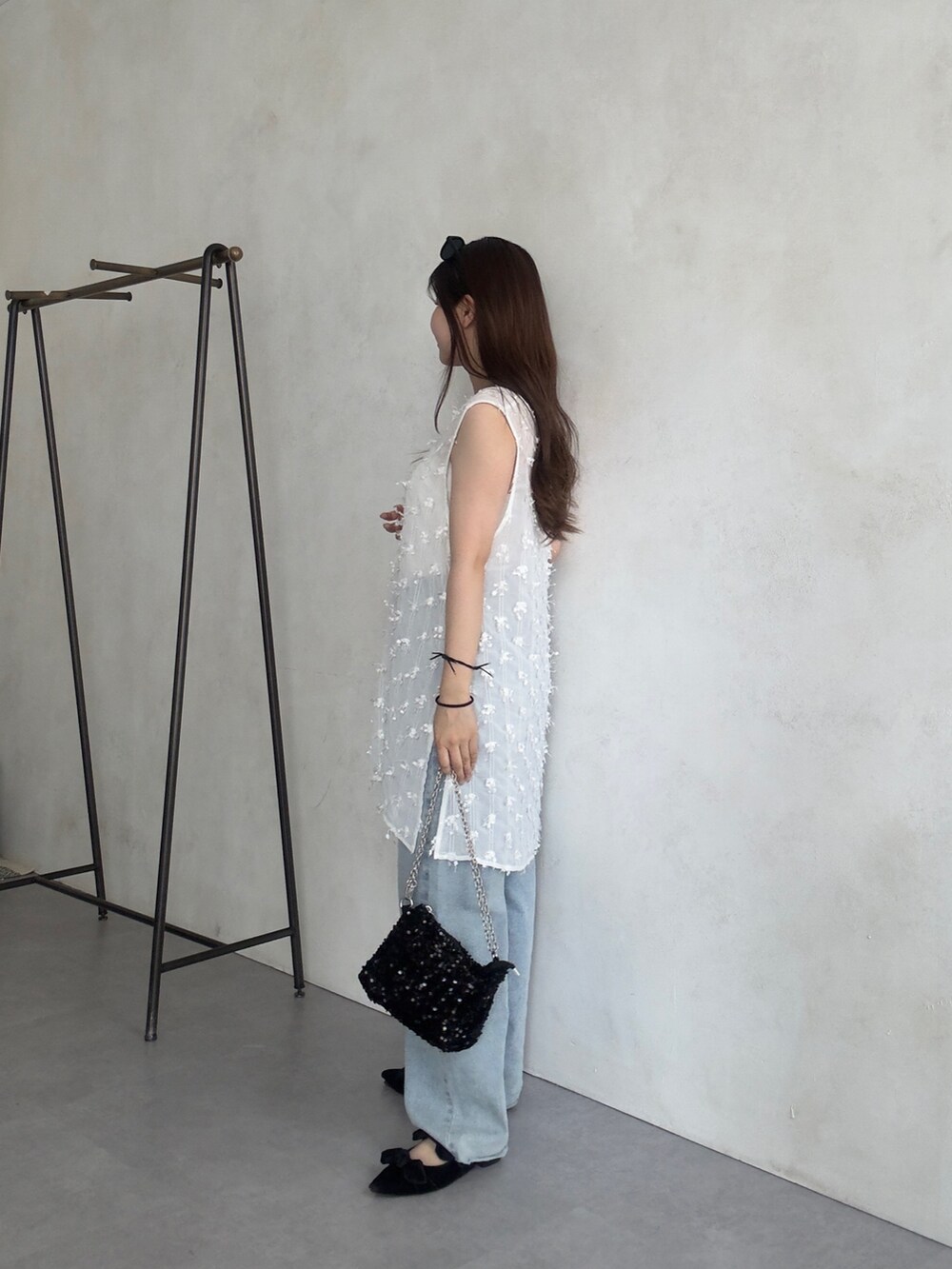 ホワイト系のベスト、ブルー系のデニムパンツを着用したレディースの夏コーディネートの2枚目の写真