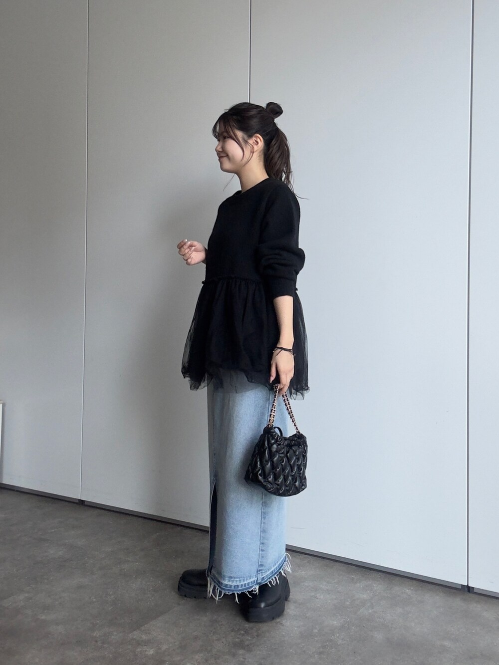 ブラック系のショルダーバッグ、ブルー系のデニムスカート、ブラック系のブーツを着用したレディースの秋コーディネートの2枚目の写真