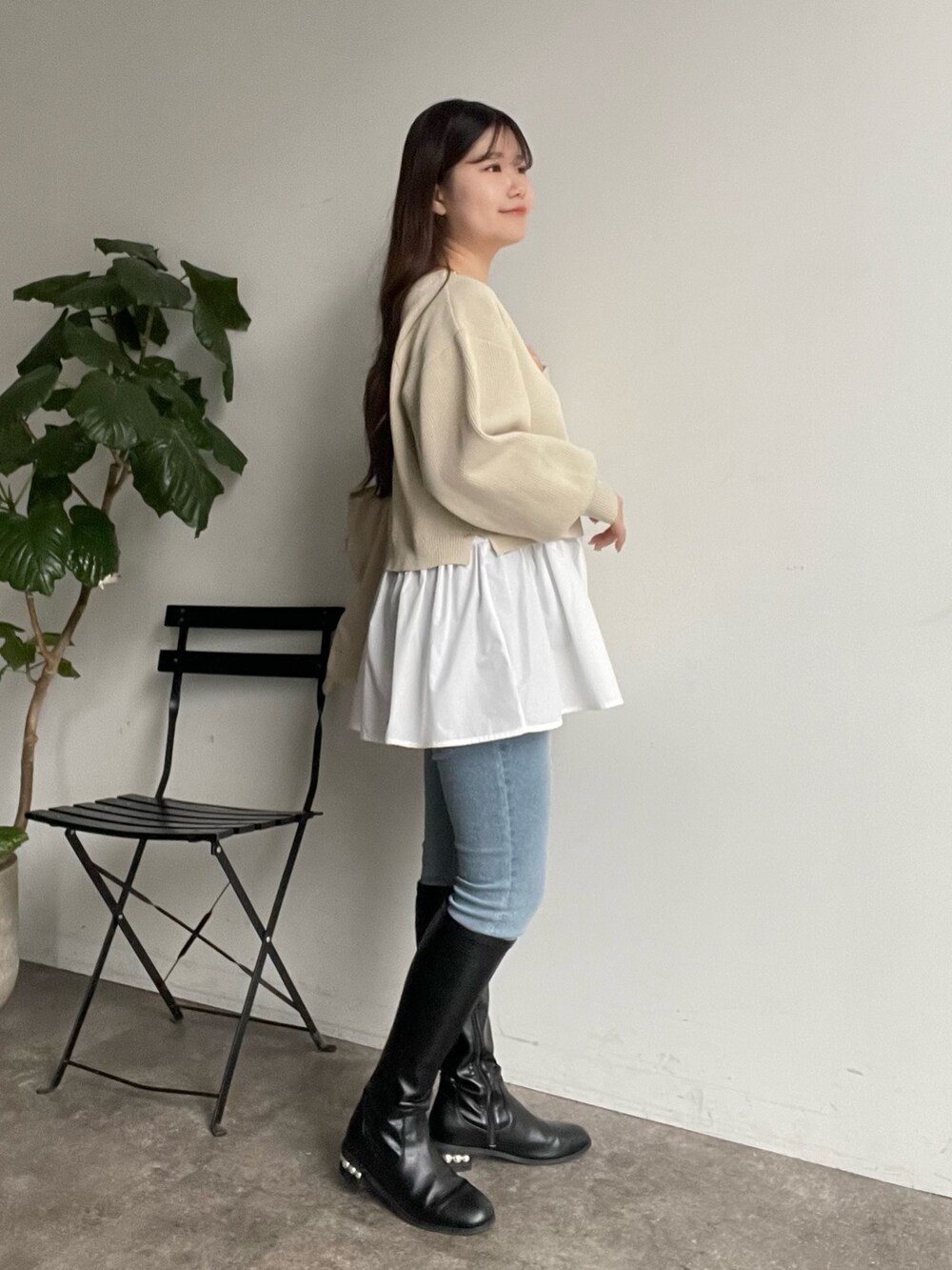 ホワイト系のカーディガン/ボレロ、ブルー系のデニムパンツ、ブラック系のブーツを着用したレディースの冬コーディネートの2枚目の写真