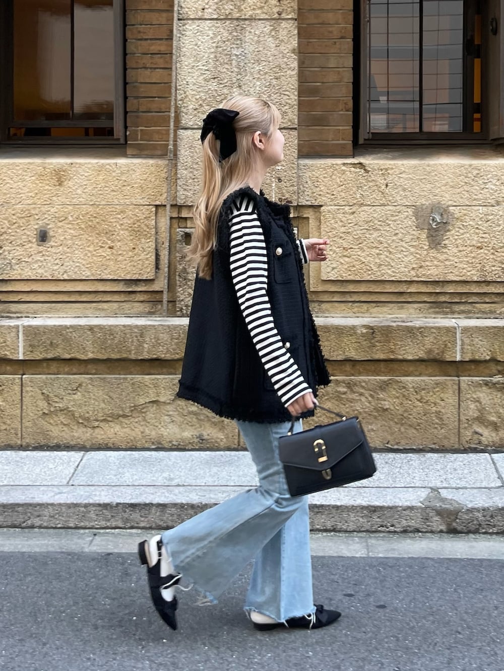 ブラック系のTシャツ/カットソー、ブラック系のベスト、ブルー系のデニムパンツを着用したレディースの秋コーディネートの2枚目の写真