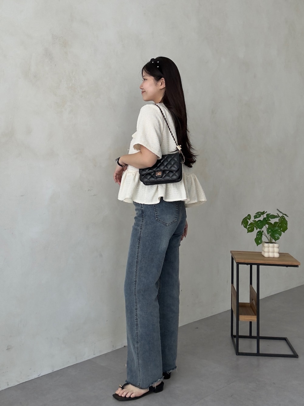 ブラック系のトートバッグ、ブルー系のデニムパンツ、ブラック系のサンダルを着用したレディースの夏コーディネートの2枚目の写真