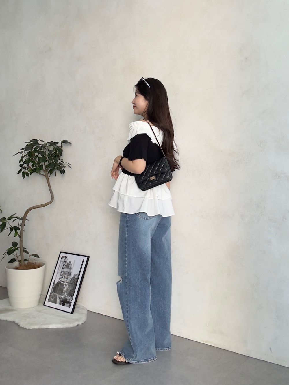 ブラック系のトートバッグ、ブルー系のデニムパンツ、ブラック系のサンダルを着用したレディースの夏コーディネートの2枚目の写真