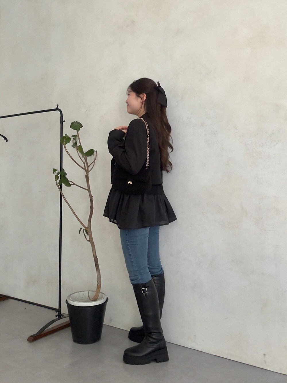 ブラック系のテーラードジャケット、ブルー系のデニムパンツ、ブラック系のブーツを着用したレディースの秋コーディネートの2枚目の写真