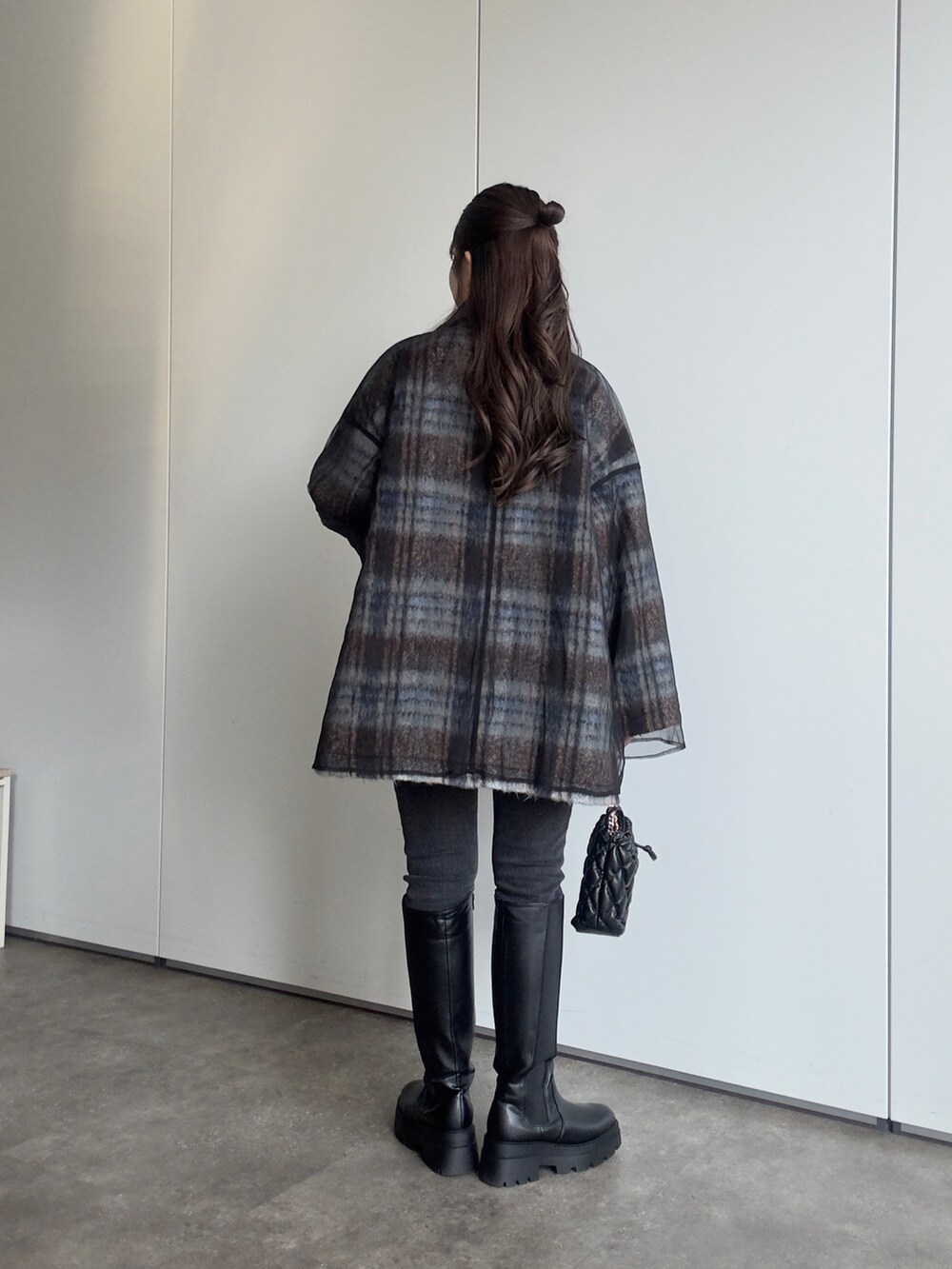 ブラック系のショルダーバッグ、ブラック系のデニムパンツ、ブラック系のブーツを着用したレディースの秋コーディネートの3枚目の写真