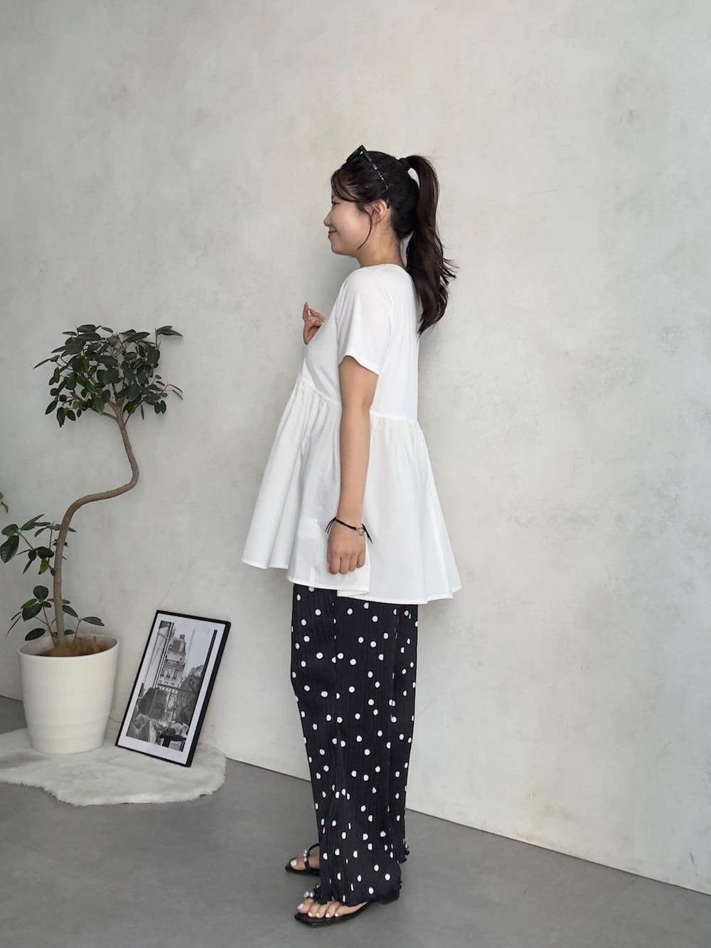 ベージュ系のかごバッグ、ブラック系のサンダル、ホワイト系のTシャツ/カットソーを着用したレディースの夏コーディネートの2枚目の写真