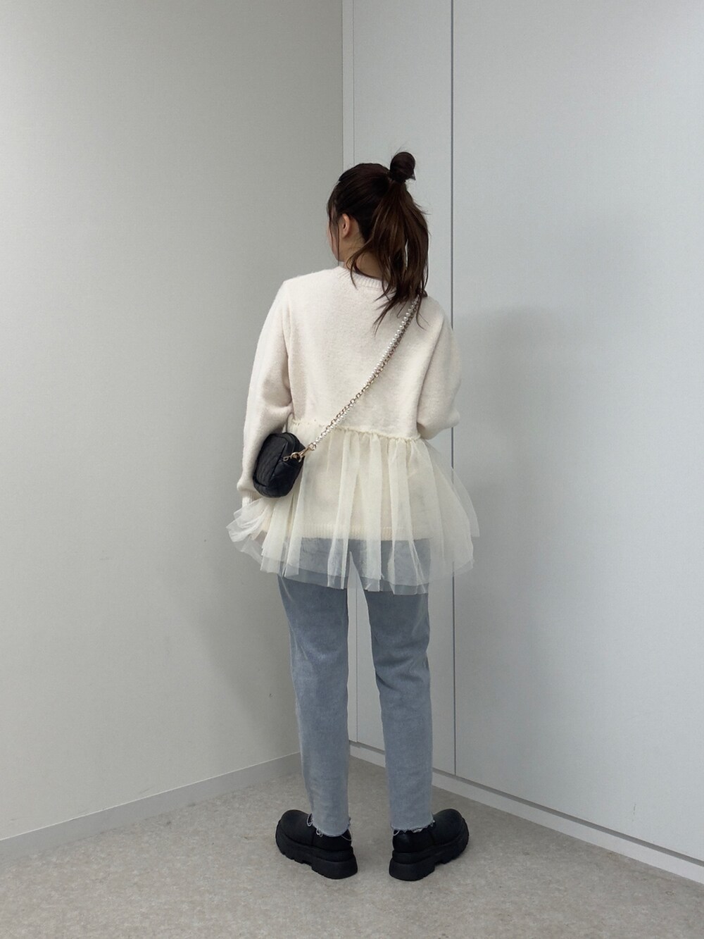 ホワイト系のニット/セーター、ブラック系のショルダーバッグ、ブルー系のデニムパンツを着用したレディースの冬コーディネートの3枚目の写真