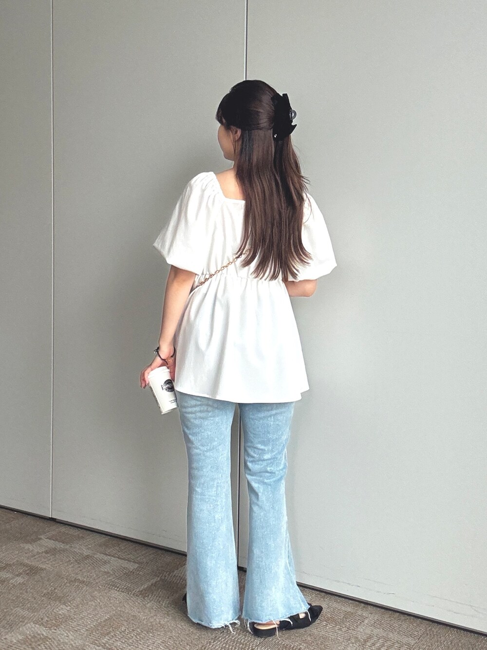 ブラック系のショルダーバッグ、ブルー系のデニムパンツ、ブラック系のパンプスを着用したレディースの春コーディネートの2枚目の写真