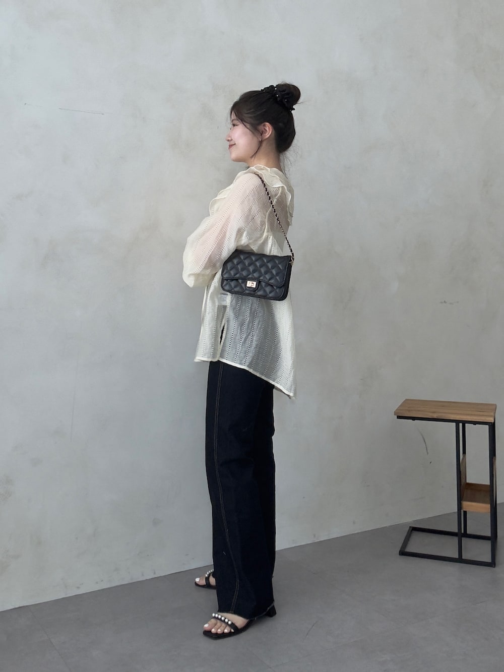 ブラック系のトートバッグ、ブルー系のデニムパンツ、ブラック系のサンダルを着用したレディースの春コーディネートの2枚目の写真