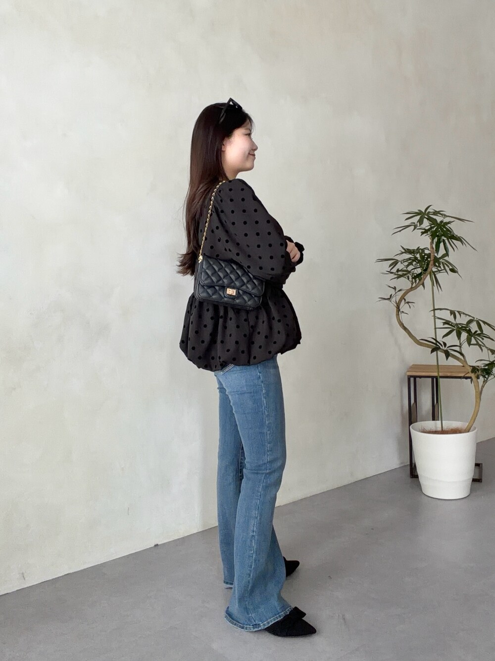 ブラック系のトートバッグ、ブルー系のデニムパンツ、ブラック系のパンプスを着用したレディースの春コーディネートの2枚目の写真