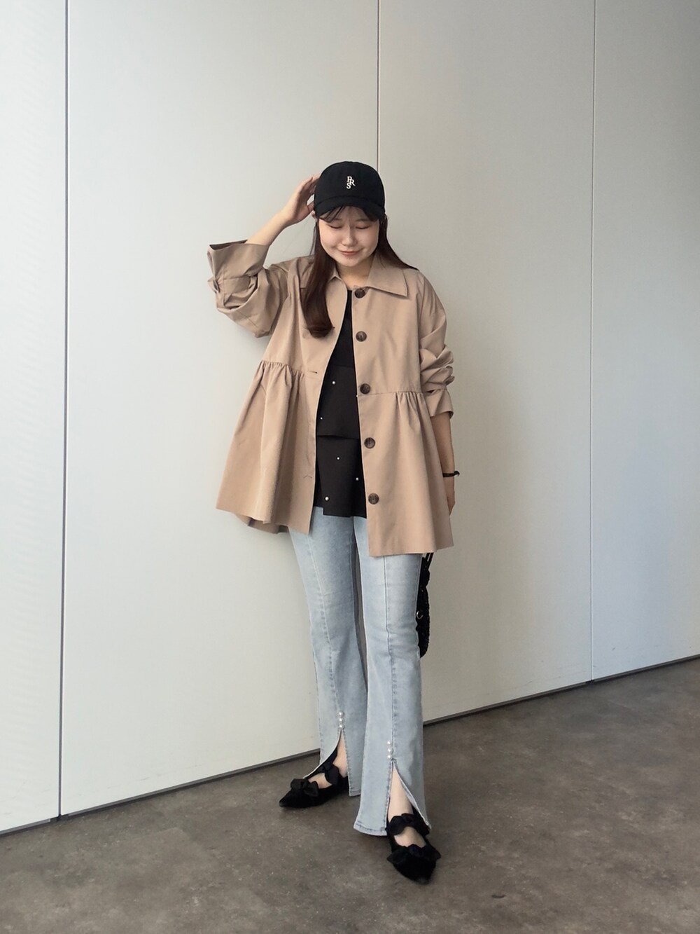 ベージュ系のトレンチコート、ブラック系のTシャツ/カットソー、ブルー系のデニムパンツを着用したレディースの春コーディネートの2枚目の写真