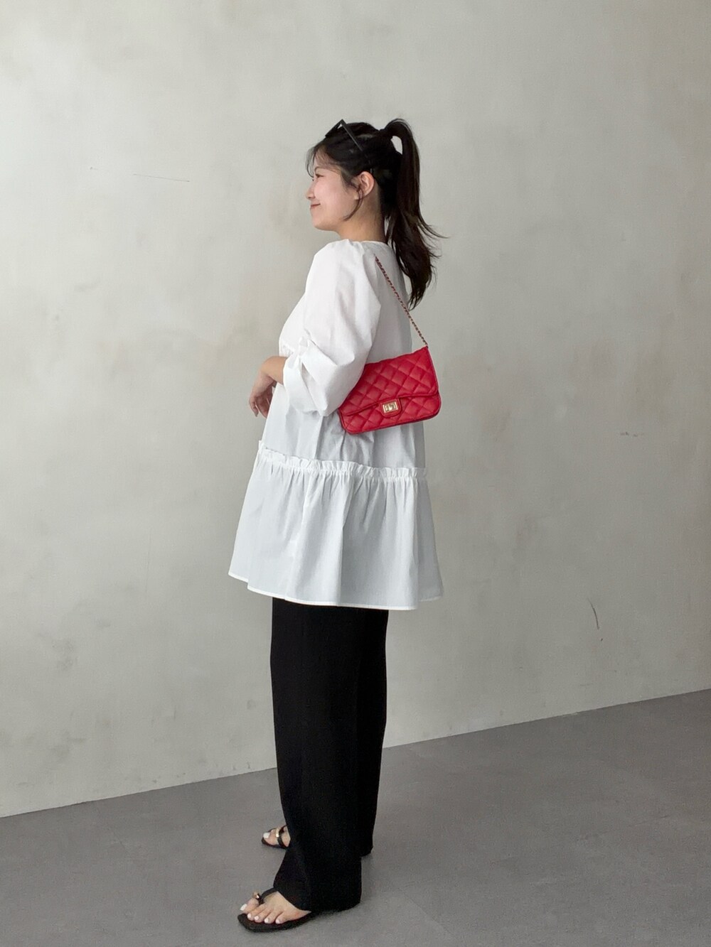 レッド系のトートバッグ、ホワイト系のシャツ/ブラウス、ブラック系のその他パンツを着用したレディースの春コーディネートの2枚目の写真