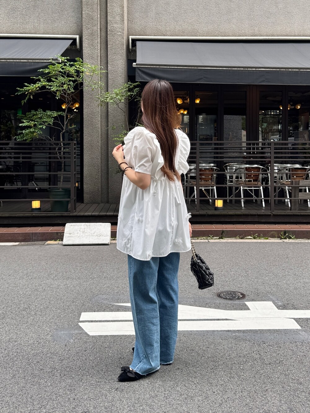 ブルー系のデニムパンツ、ブラック系のパンプス、ホワイト系のシャツ/ブラウスを着用したレディースの夏コーディネートの3枚目の写真