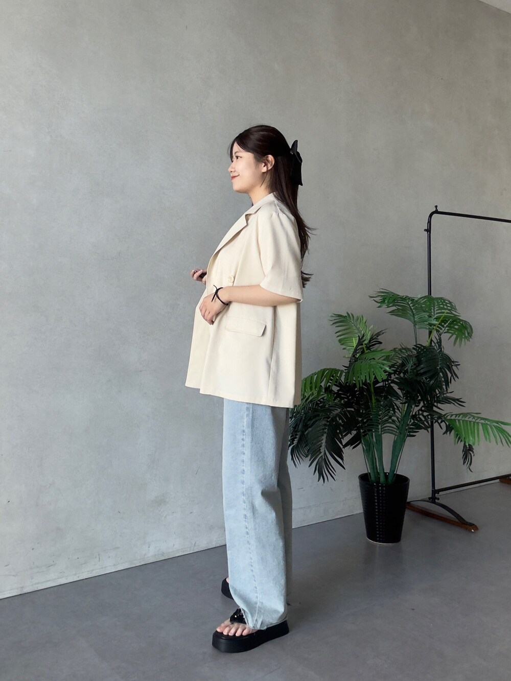 ブラック系のテーラードジャケット、ホワイト系のTシャツ/カットソー、ブルー系のデニムパンツを着用したレディースの夏コーディネートの2枚目の写真