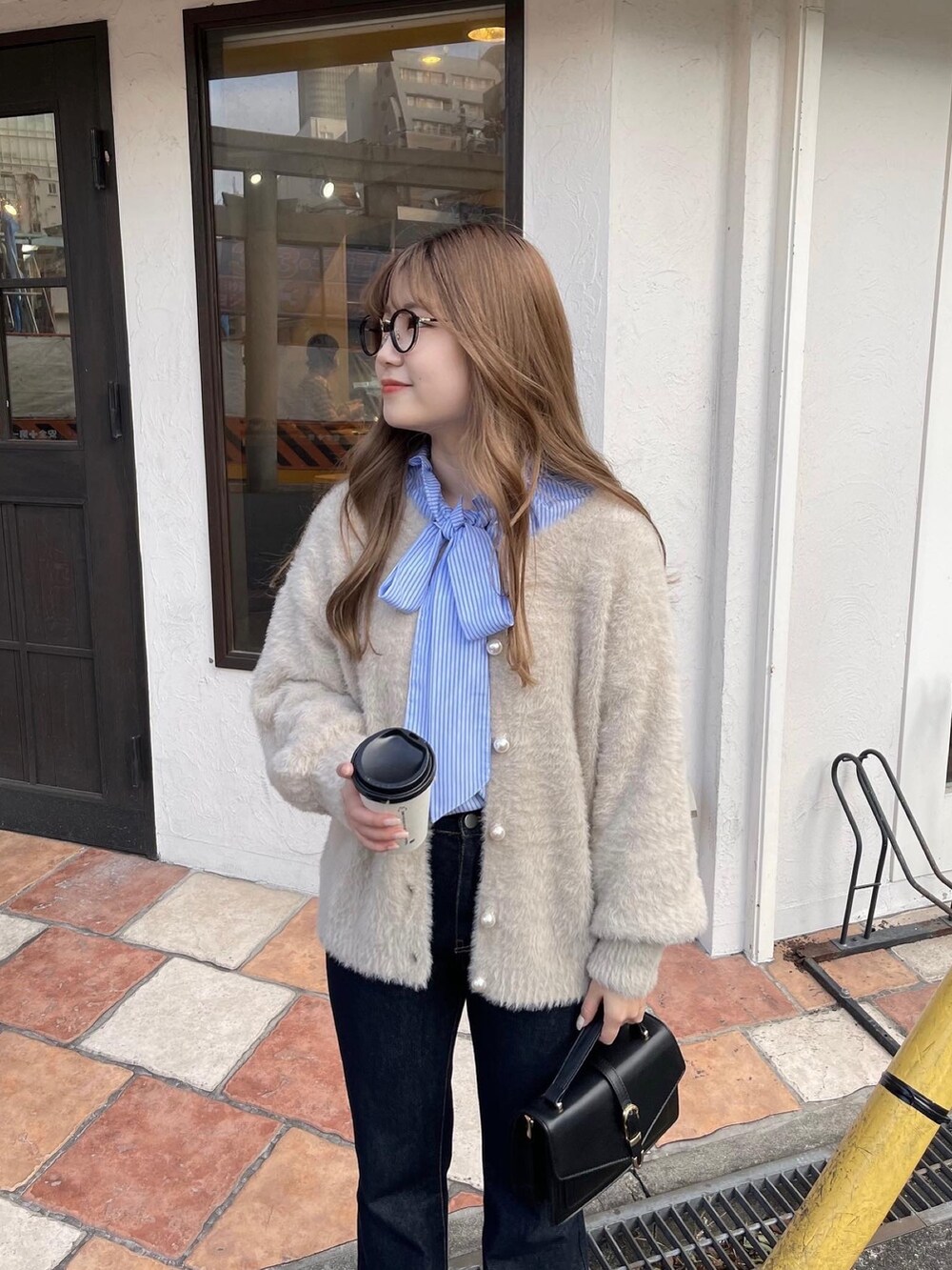 ブルー系のシャツ/ブラウス、ベージュ系のカーディガン/ボレロ、ブルー系のデニムパンツを着用したレディースの冬コーディネートの4枚目の写真