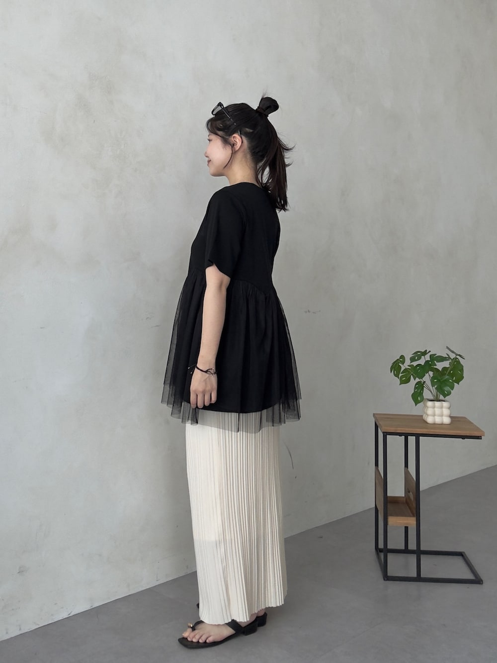 ブラック系のサンダル、ブラック系のTシャツ/カットソー、ホワイト系のスカートを着用したレディースの夏コーディネートの2枚目の写真