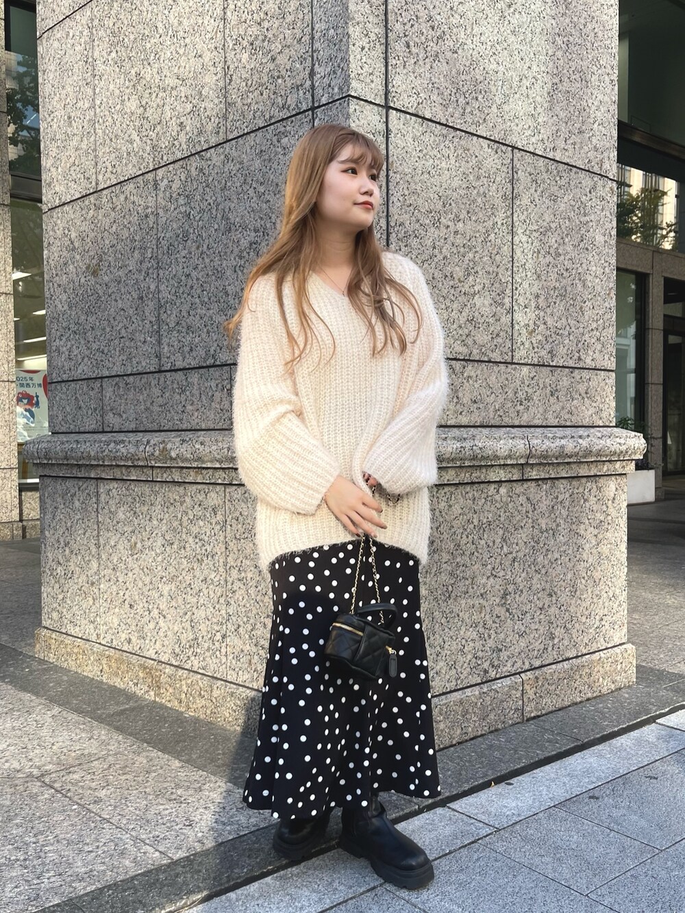 ベージュ系のニット/セーター、ブラック系のブーツ、ブラック系のショルダーバッグを着用したレディースの秋コーディネートの3枚目の写真