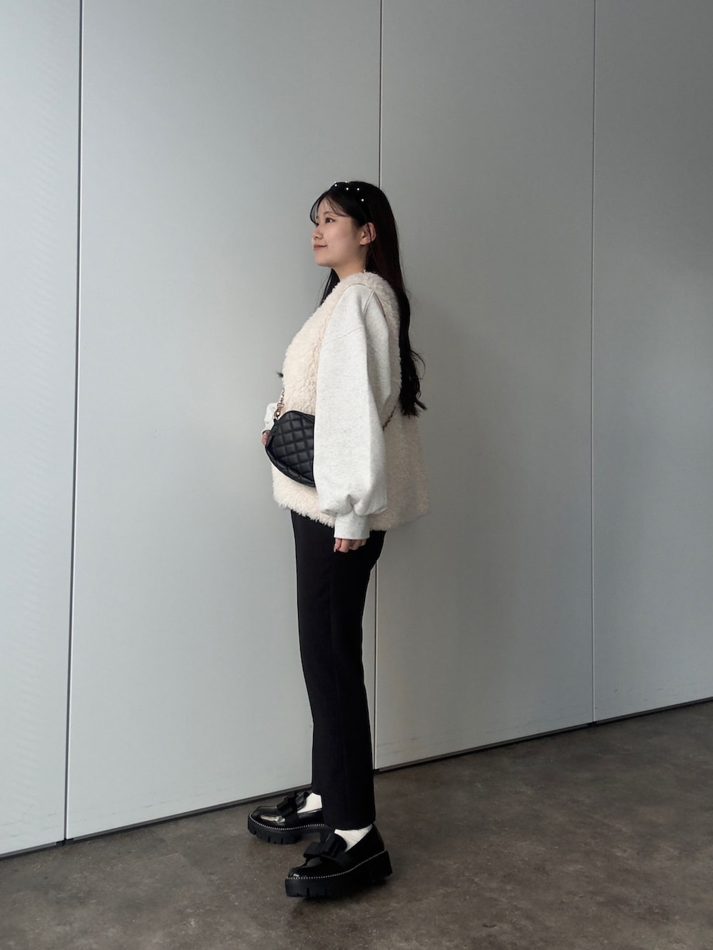 グレー系のスウェット、ホワイト系のベスト、ブラック系のその他パンツを着用したレディースの秋コーディネートの2枚目の写真