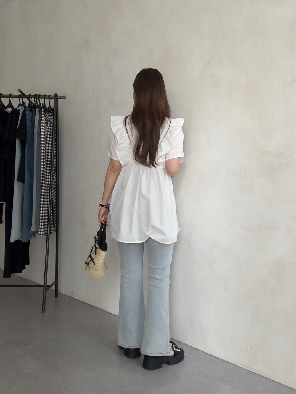 ブラック系のかごバッグ、ブルー系のデニムパンツ、ブラック系のサンダルを着用したレディースの夏コーディネートの3枚目の写真