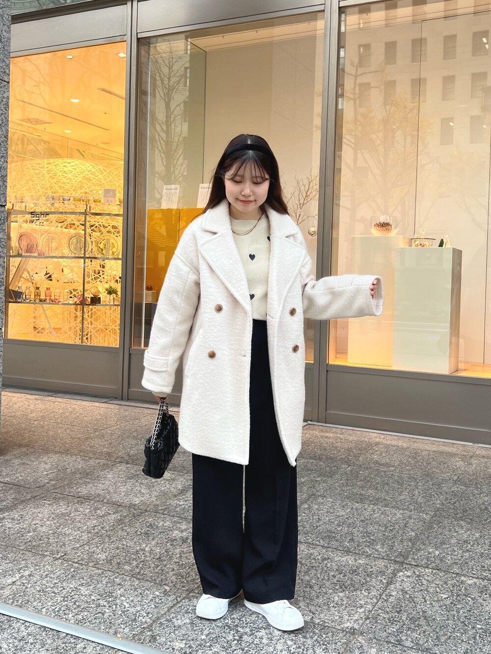 ベージュ系のニット/セーター、ブラック系のスラックス、ホワイト系のピーコートを着用したレディースの冬コーディネートの3枚目の写真