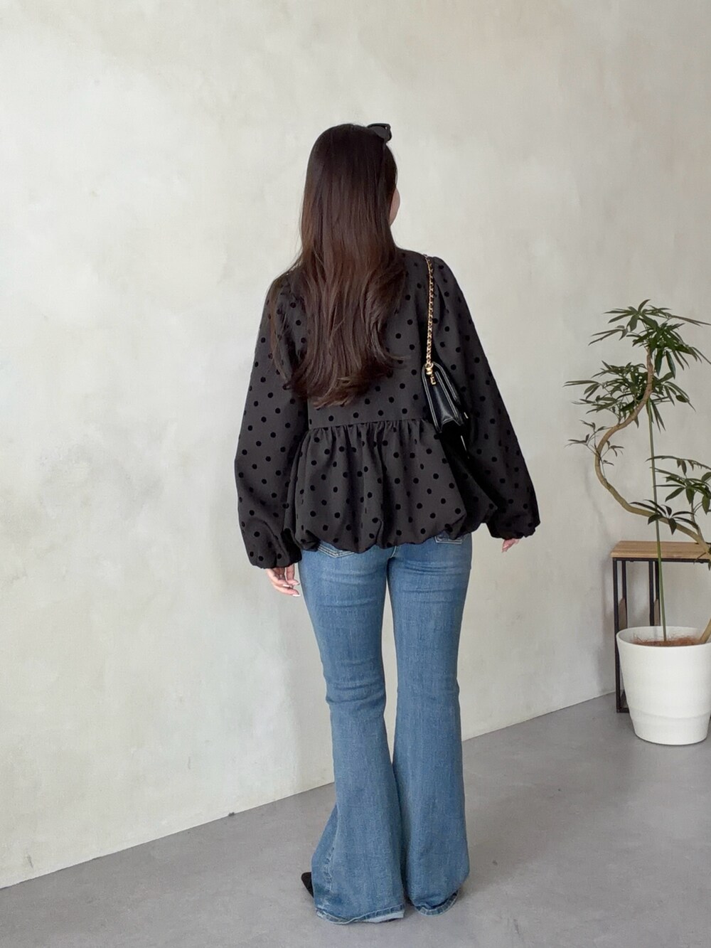 ブラック系のトートバッグ、ブルー系のデニムパンツ、ブラック系のパンプスを着用したレディースの春コーディネートの3枚目の写真