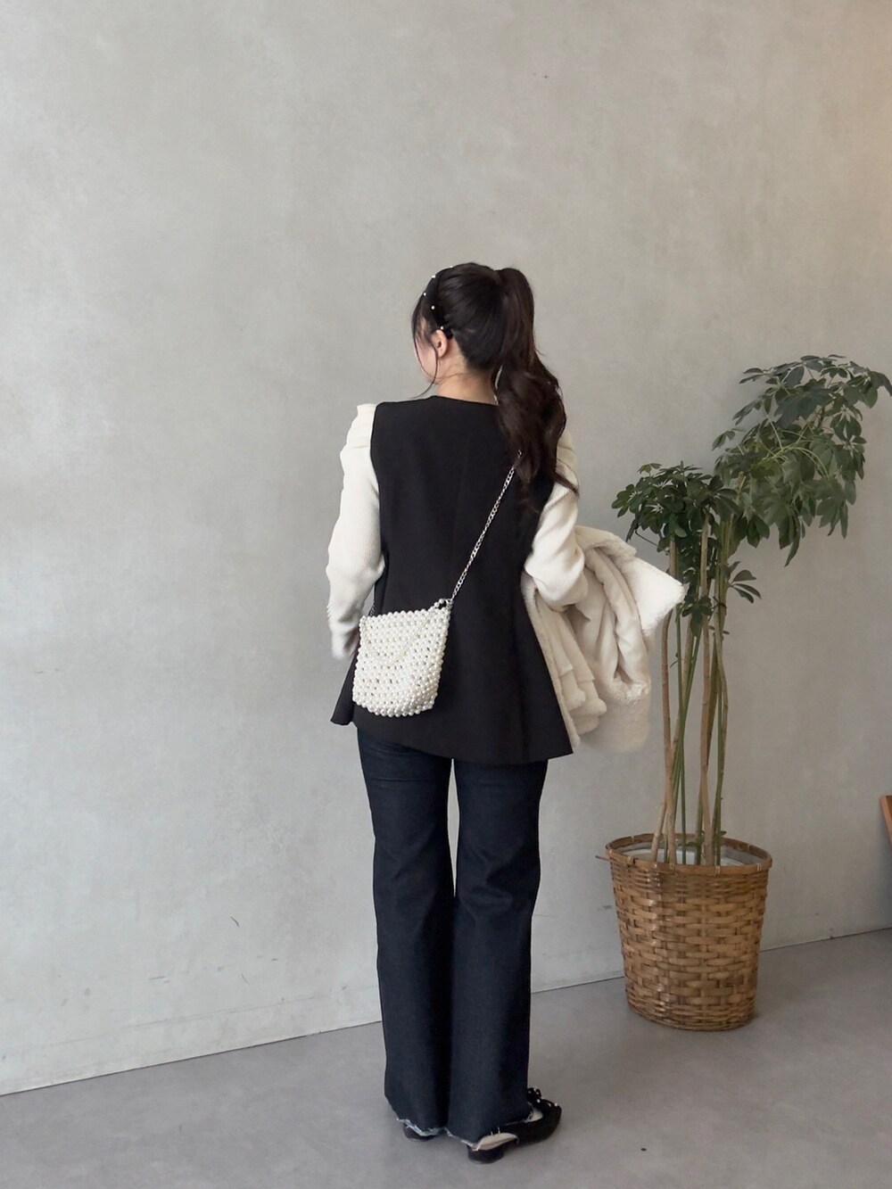 ホワイト系のニット/セーター、ブルー系のデニムパンツ、ブラック系のベストを着用したレディースの秋コーディネートの3枚目の写真