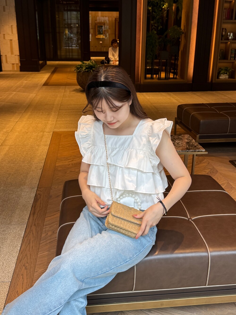 ホワイト系のシャツ/ブラウス、ベージュ系のショルダーバッグ、ブルー系のデニムパンツを着用したレディースの夏コーディネートの3枚目の写真