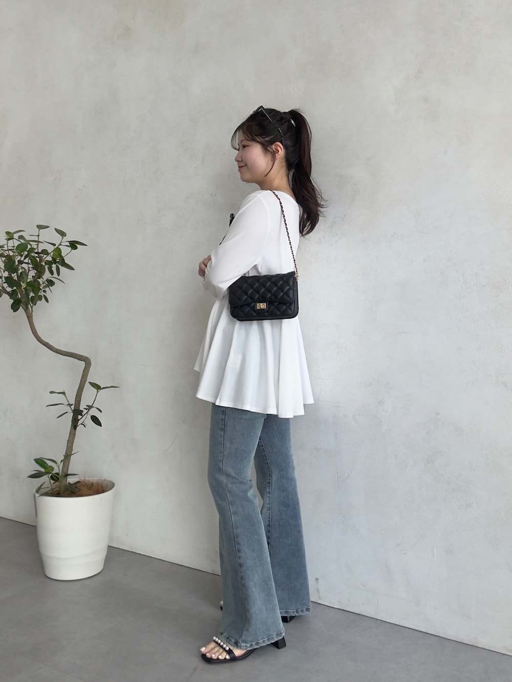 ブラック系のトートバッグ、ブルー系のデニムパンツ、ブラック系のサンダルを着用したレディースの春コーディネートの2枚目の写真