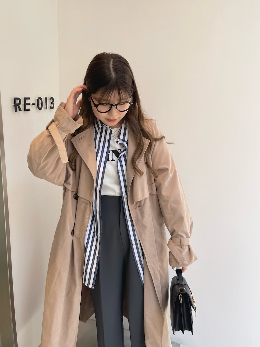 ベージュ系のトレンチコート、ブルー系のシャツ/ブラウス、ホワイト系のTシャツ/カットソーを着用したレディースの春コーディネートの2枚目の写真
