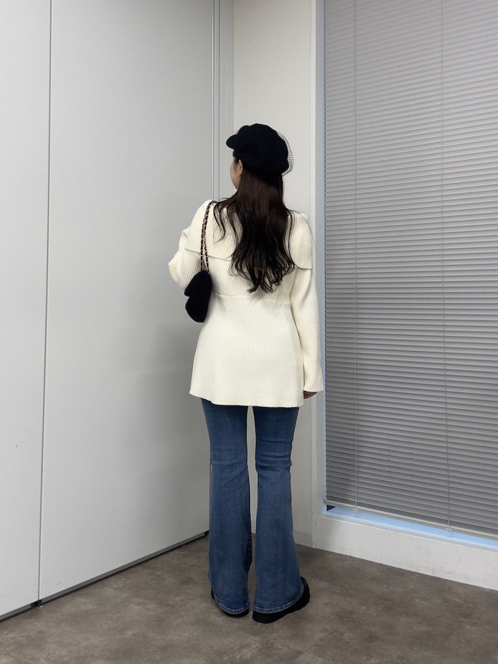 ブラック系のショルダーバッグ、ホワイト系のニット/セーター、ブルー系のデニムパンツを着用したレディースの秋コーディネートの3枚目の写真