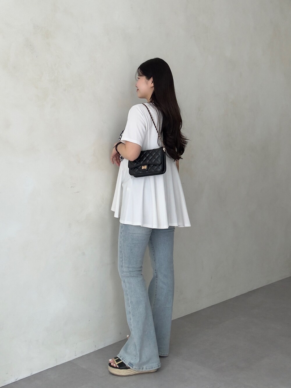 ブラック系のトートバッグ、ブルー系のデニムパンツ、ブラック系のサンダルを着用したレディースの夏コーディネートの2枚目の写真