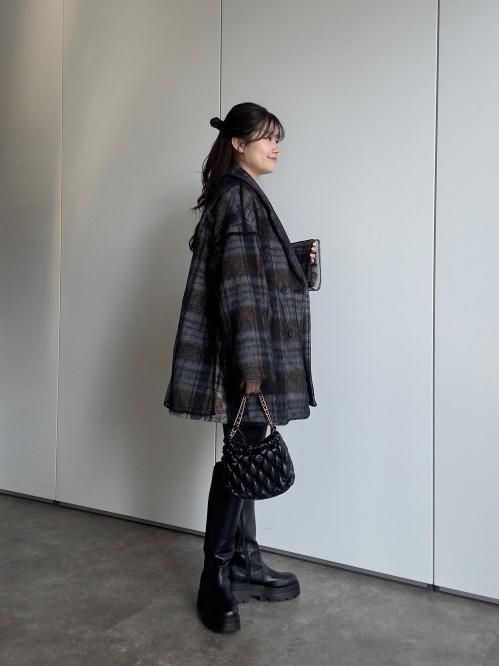 ブラック系のショルダーバッグ、ブラック系のデニムパンツ、ブラック系のブーツを着用したレディースの秋コーディネートの2枚目の写真