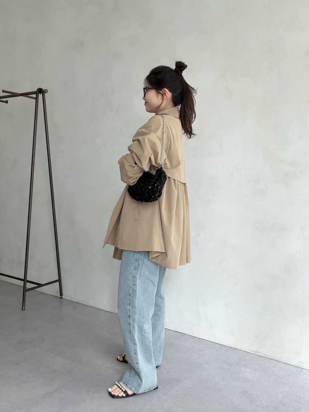 ベージュ系のトレンチコート、ブラック系のサンダル、ホワイト系のTシャツ/カットソーを着用したレディースの春コーディネートの2枚目の写真