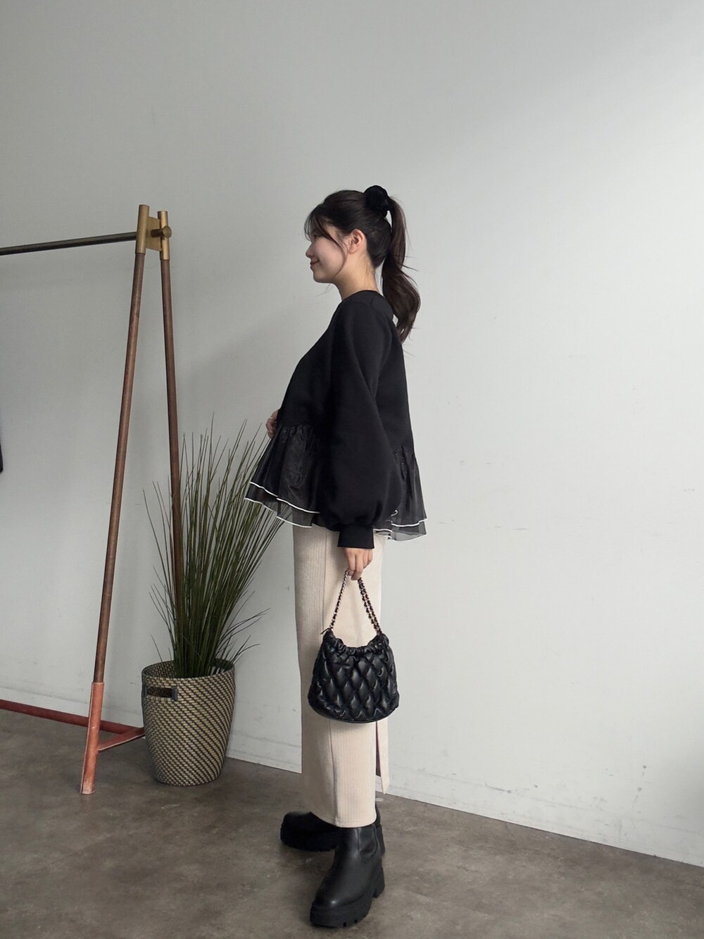 ブラック系のスウェット、ブラック系のブーツ、ベージュ系のスカートを着用したレディースの秋コーディネートの2枚目の写真