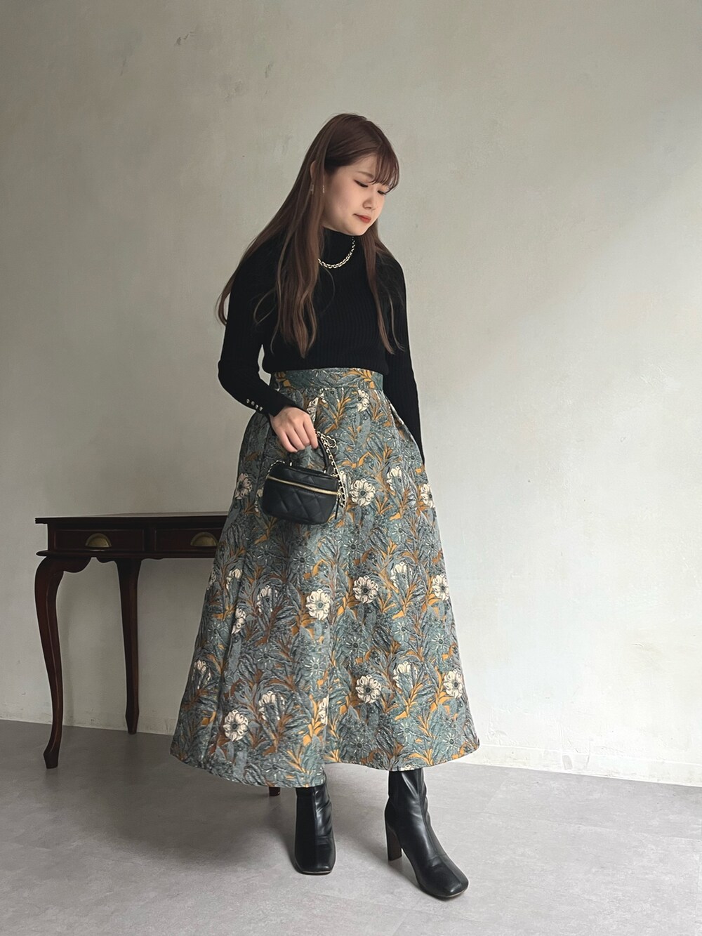 イエロー系のスカート、ブラック系のニット/セーター、ブラック系のショルダーバッグを着用したレディースの秋コーディネートの2枚目の写真