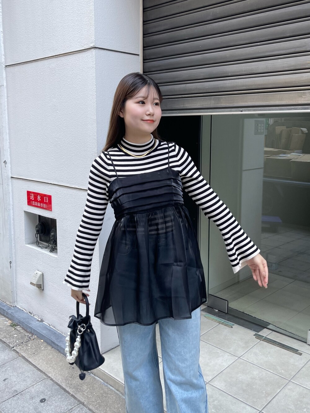 ホワイト系のニット/セーター、ブラック系のショルダーバッグ、ブラック系のキャミソールを着用したレディースの冬コーディネートの4枚目の写真