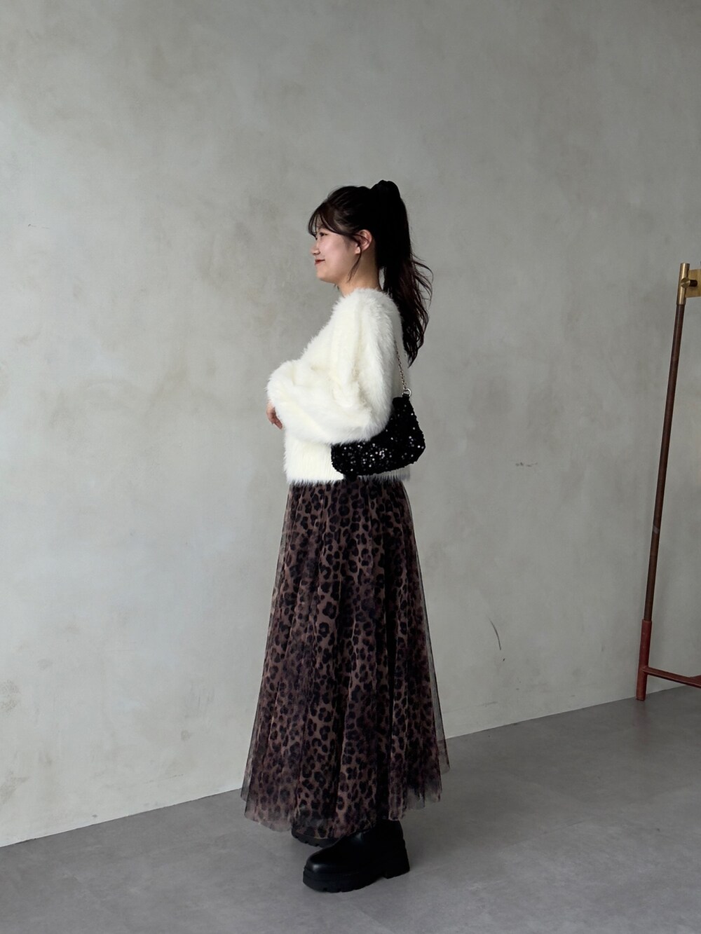 ホワイト系のカーディガン/ボレロ、ブラウン系のスカート、ブラック系のブーツを着用したレディースの秋コーディネートの2枚目の写真