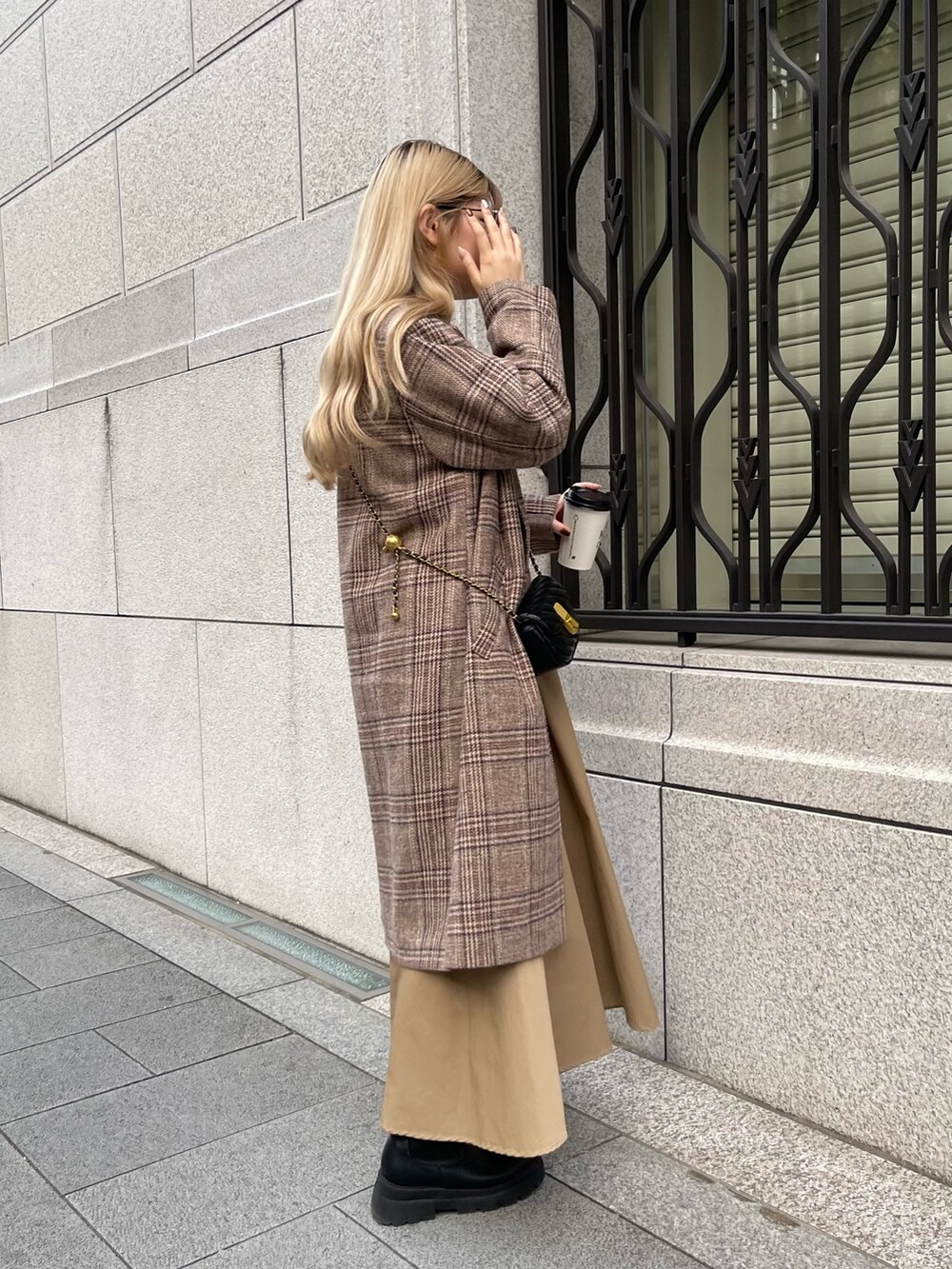 ホワイト系のニット/セーター、ブラウン系のチェスターコート、ベージュ系のスカートを着用したレディースの秋コーディネートの4枚目の写真