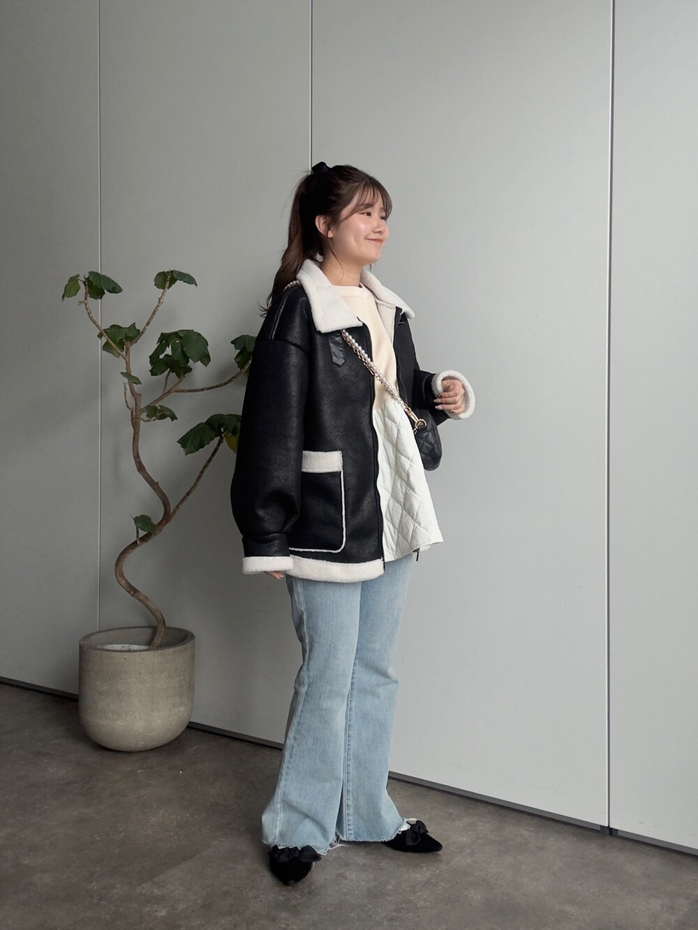 ブラック系のムートンコート、ベージュ系のTシャツ/カットソー、ブラック系のショルダーバッグを着用したレディースの冬コーディネートの2枚目の写真