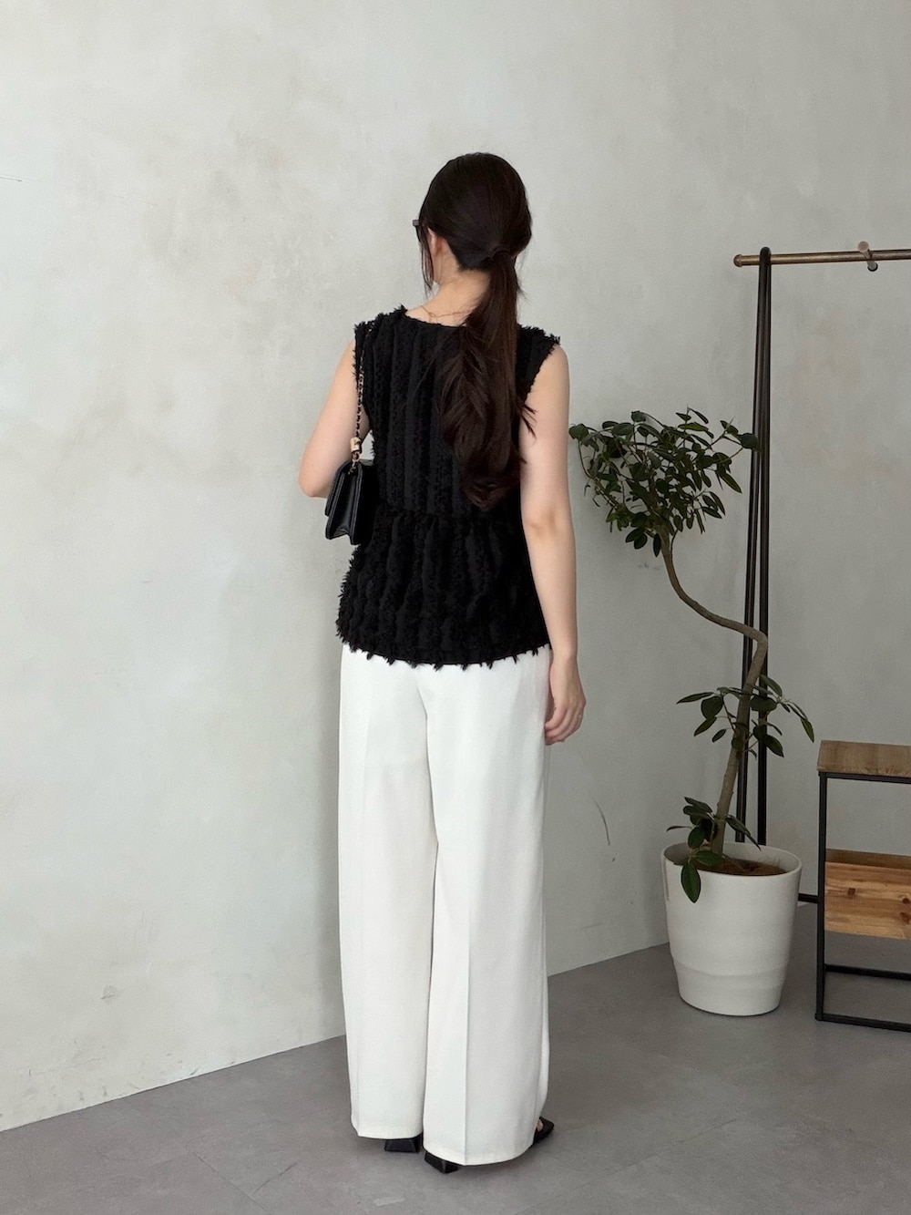 ブラック系のトートバッグ、ホワイト系のスラックス、ブラック系のサンダルを着用したレディースの夏コーディネートの3枚目の写真