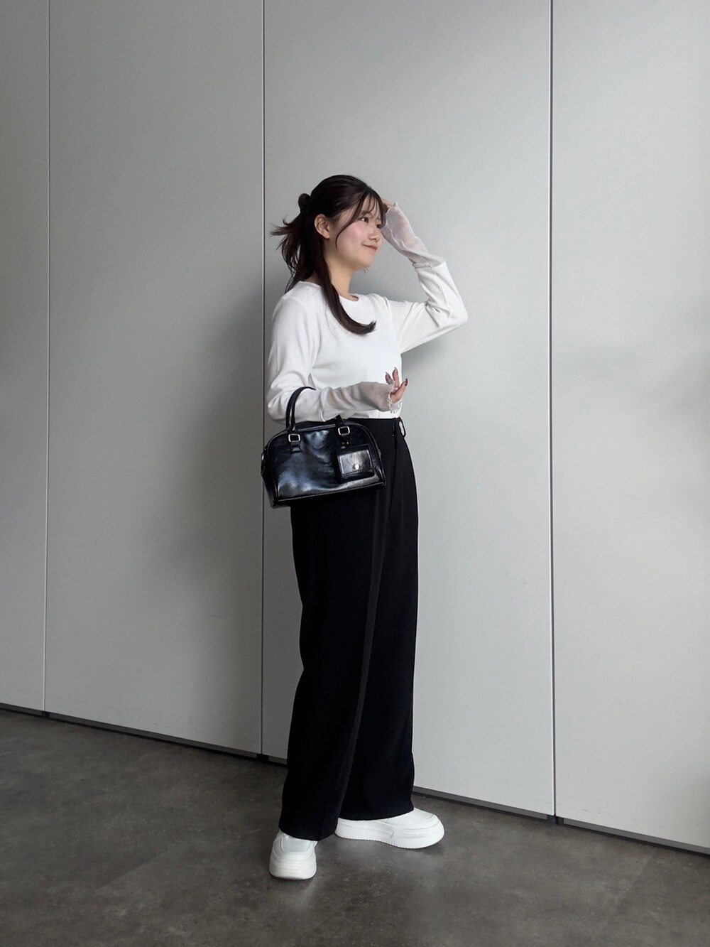 ホワイト系のTシャツ/カットソー、ブラック系のスラックス、ブラック系のボストンバッグを着用したレディースの春コーディネートの3枚目の写真