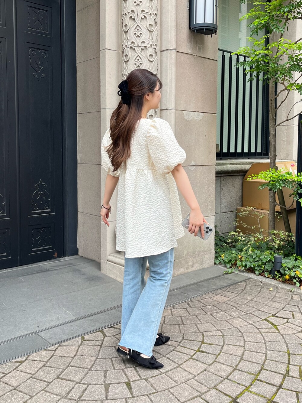 ブラック系のショルダーバッグ、ブルー系のデニムパンツ、ブラック系のパンプスを着用したレディースの春コーディネートの3枚目の写真