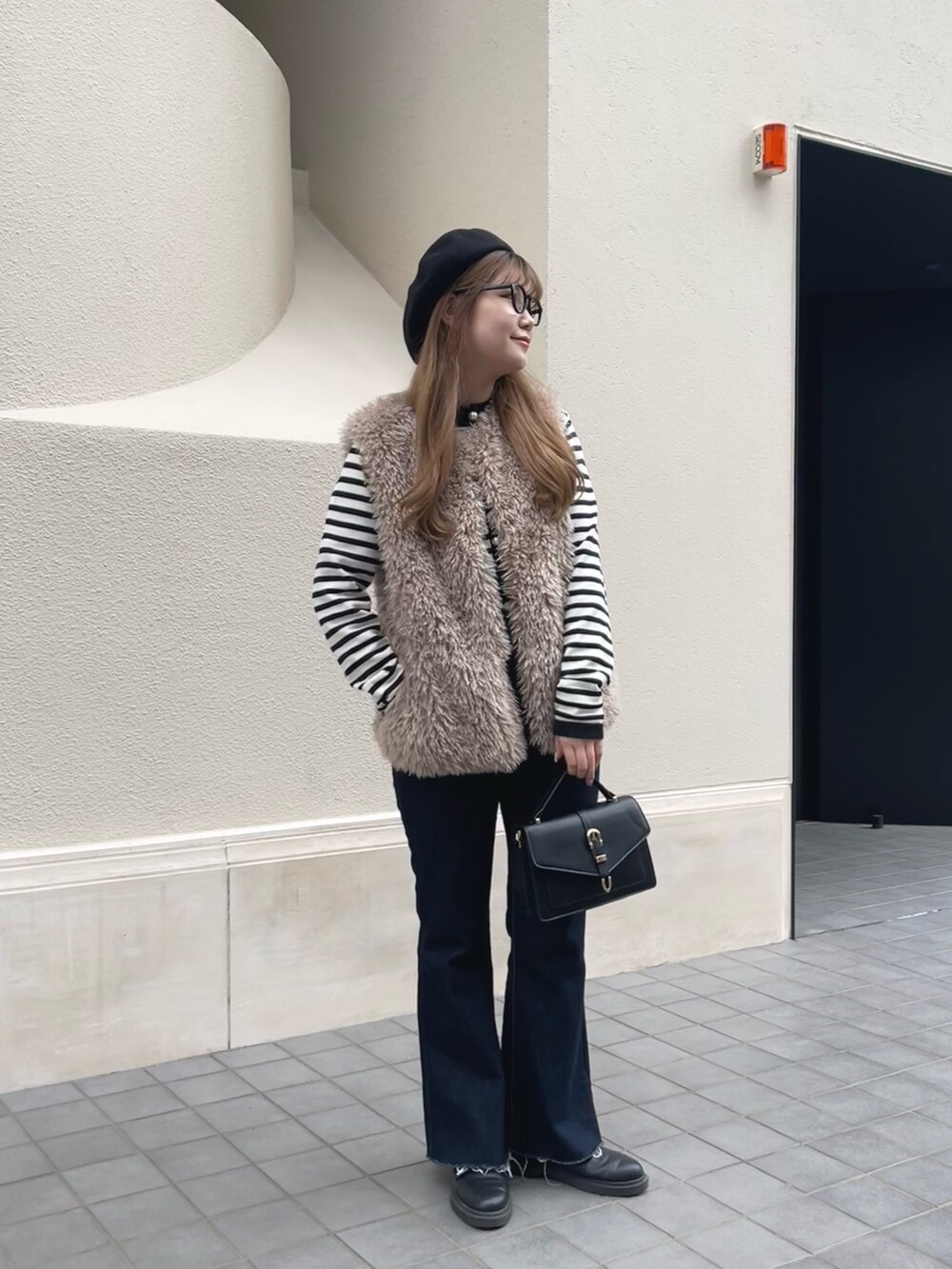 ブルー系のデニムパンツ、ベージュ系のベスト、ホワイト系のカーディガン/ボレロを着用したレディースの冬コーディネートの3枚目の写真