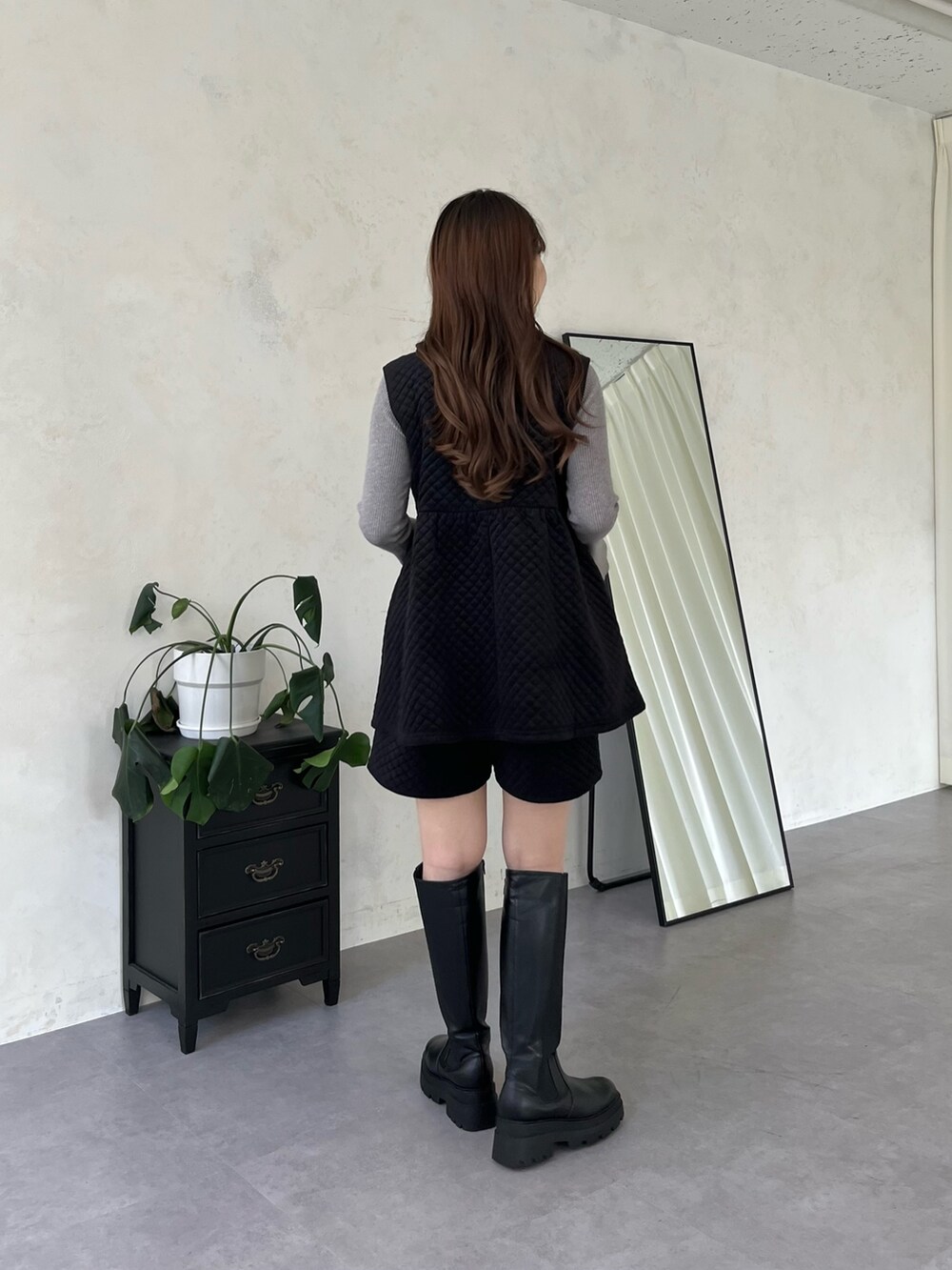 ホワイト系のニット/セーター、ブラック系のブーツ、ブラック系のショルダーバッグを着用したレディースの秋コーディネートの2枚目の写真