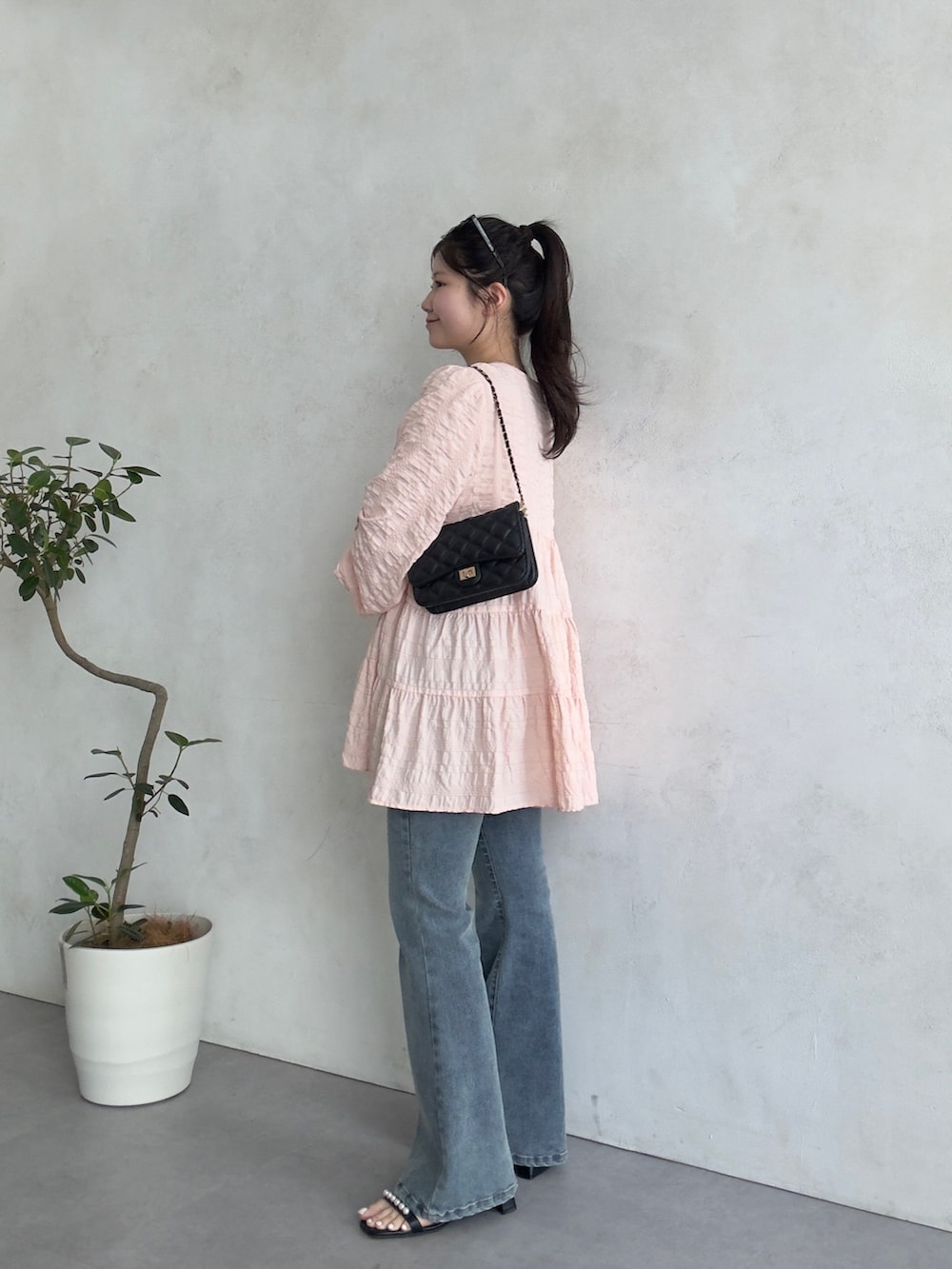 ブラック系のトートバッグ、ブルー系のデニムパンツ、ブラック系のサンダルを着用したレディースの春コーディネートの2枚目の写真