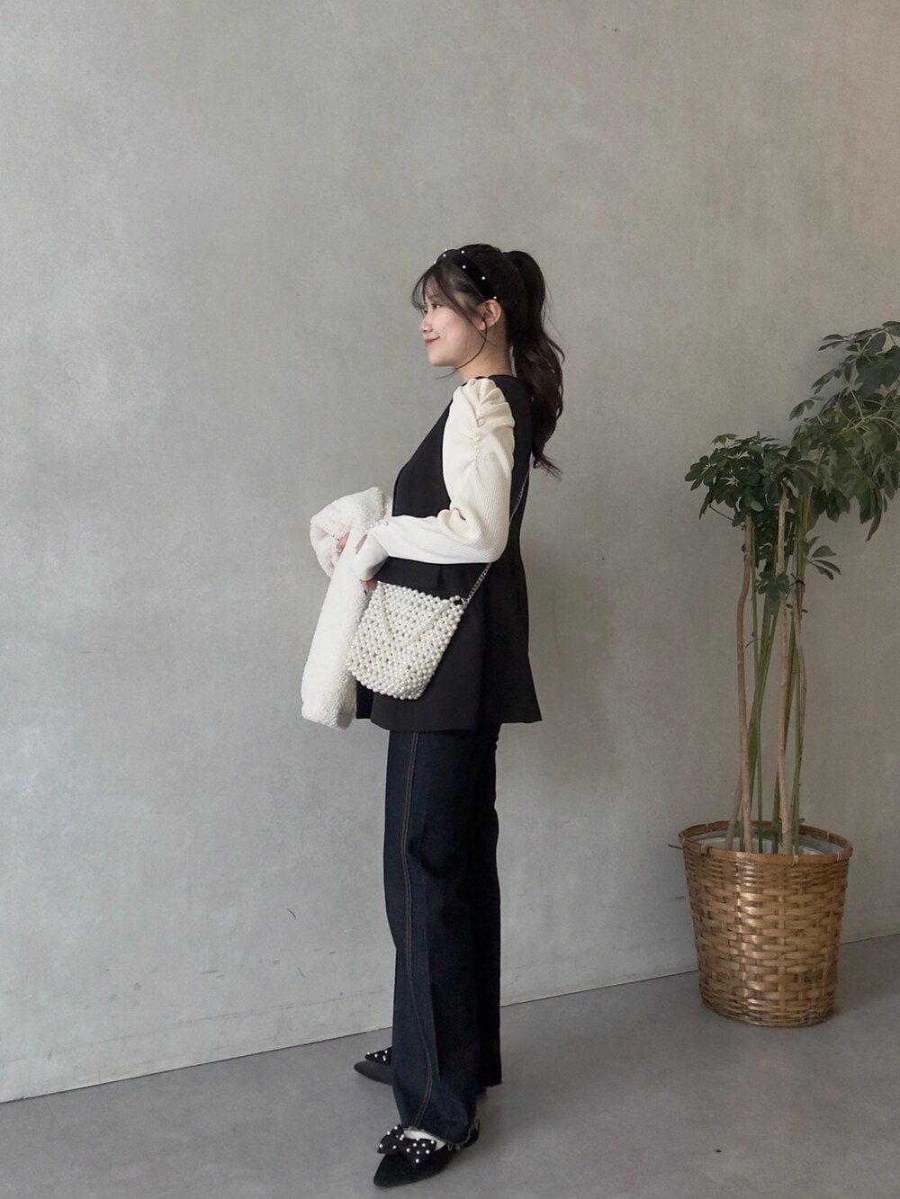 ホワイト系のニット/セーター、ブルー系のデニムパンツ、ブラック系のベストを着用したレディースの秋コーディネートの2枚目の写真