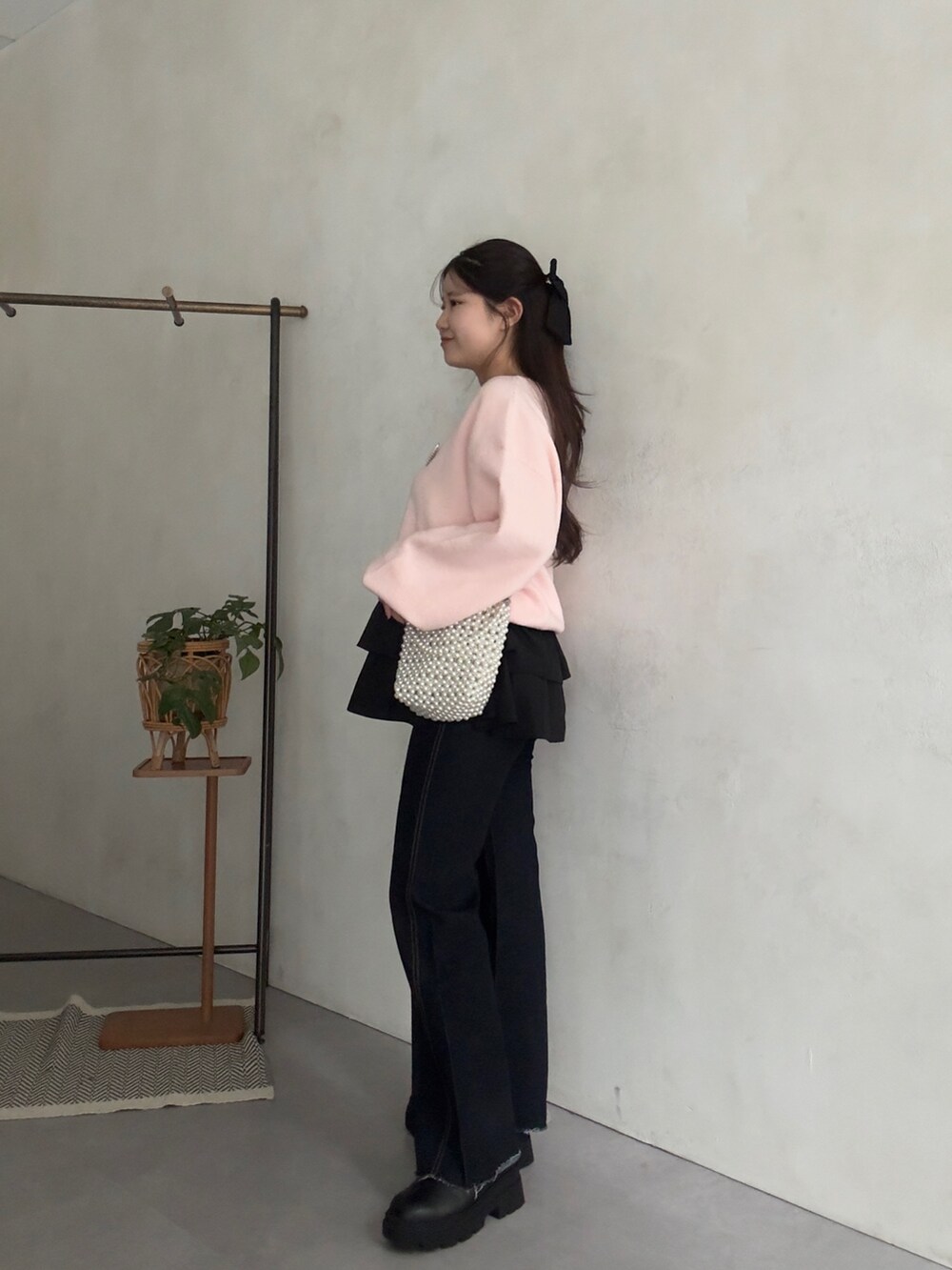 ピンク系のニット/セーター、ブラック系のスカート、ブルー系のデニムパンツを着用したレディースの秋コーディネートの2枚目の写真