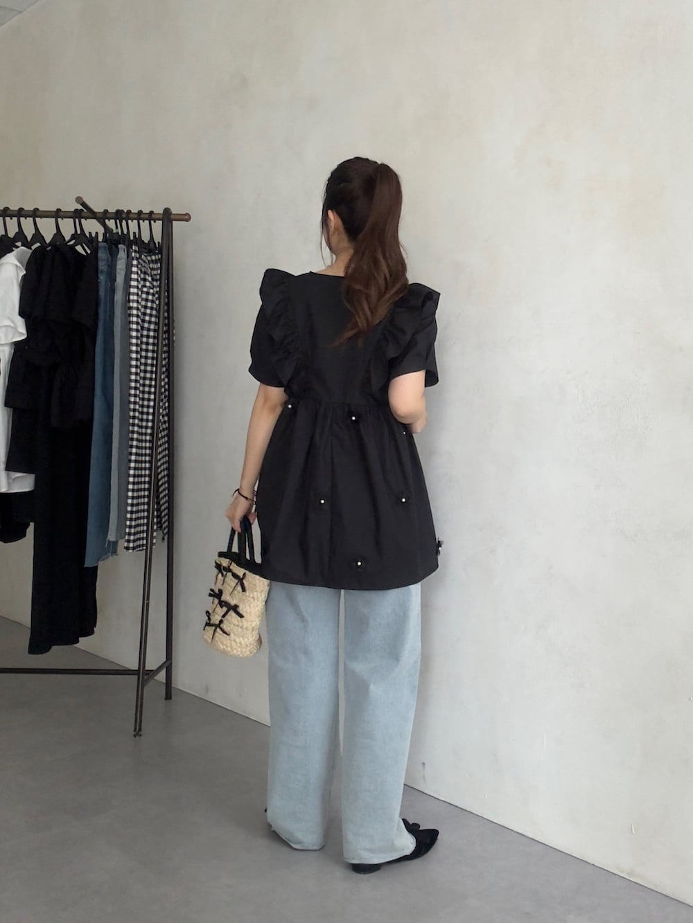 ブラック系のかごバッグ、ブルー系のデニムパンツ、ブラック系のパンプスを着用したレディースの夏コーディネートの3枚目の写真